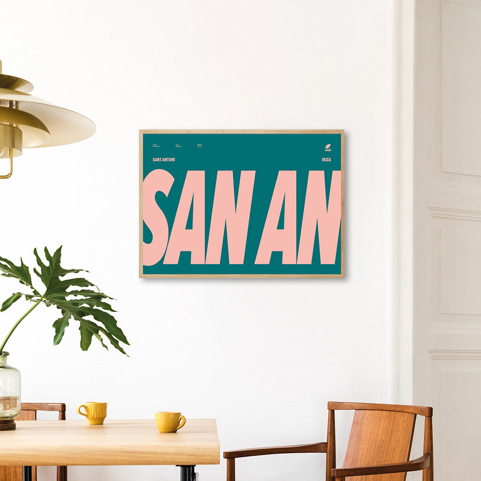 Framed Minimal style Ibiza typography print with the words San An for San Antonio in peachy pink on a bluey green background.